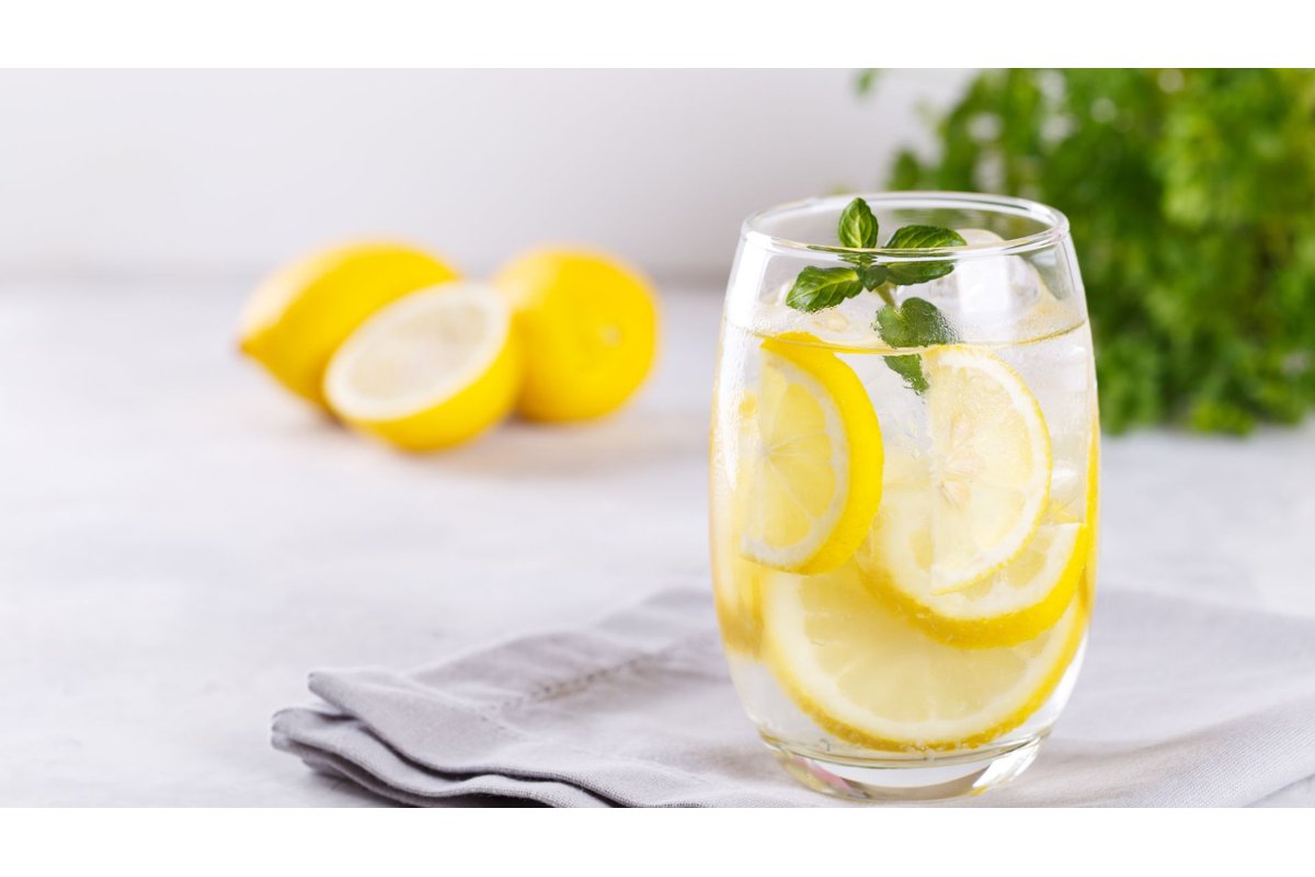 Tazza di tè con spezie e fette di limone su tavolo di legno.